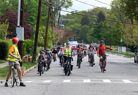 Adults lead kids in bike bus signaling a left turn